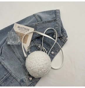 Detail view of a white plush spherical crossbody bag with beaded handle and leather strap