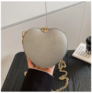 Macro detail of heart-shaped silver sequin evening bag with gold chain and dual heart zippers