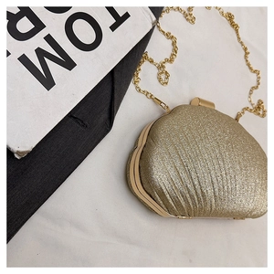 Détail d'un sac de soirée coquillage doré à paillettes avec une fine bandoulière chaîne