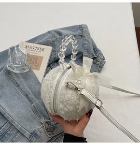 Detail of white plush sphere bag featuring transparent bead handle and satin bow