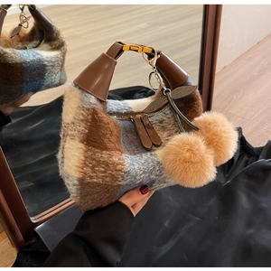 Detail der karierten Handtasche mit Plüschtextur und kirschförmigem Fellknäuel-Anhänger