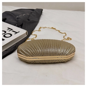 Détail de pochette de soirée dorée avec texture plissée coquille et chaîne en métal