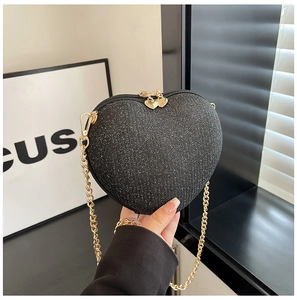 Close-up of heart-shaped clutch bag with black glitter finish and gold chain strap