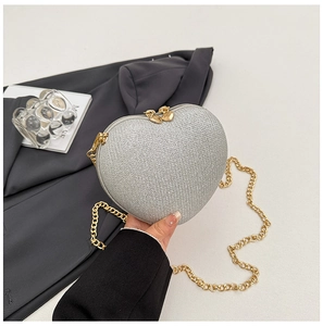Detail of silver heart evening bag with glitter texture and gold chain strap