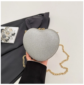 Detail of silver heart-shaped bag with fine glitter texture and gold chain strap