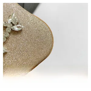 Detail of gold glitter evening clutch with rhinestone leaf buckle and fine sequin fabric