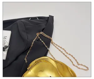 Detail of the high-polish gold acrylic evening bag with a delicate metallic chain strap