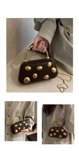 Detail van vintage bruine box-tas met gouden accenten en spiraalvormig metalen handvat