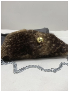 Detail of plush faux fur texture on brown crossbody bag with gold spherical accent