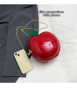 Size comparison of a red apple shaped glossy crossbody bag with a gold chain strap