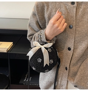 Detail of black faux fur ball bag with white bow and transparent acrylic flowers