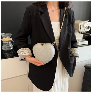 Detail of silver heart-shaped crossbody bag with glitter texture and gold chain strap