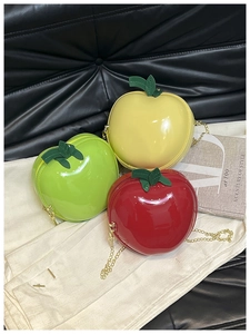 Détail de mini sacs en forme de pomme rouge, jaune et vert avec des chaînes dorées