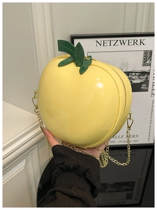 Détail du mini sac pomme jaune avec finition brillante et chaîne dorée