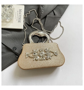 Detail of gold glitter evening clutch with floral rhinestone decor and metal handle