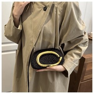 Close-up of black velvet evening clutch with gold C-logo buckle and delicate chain