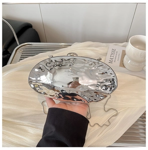 Dettaglio borsa da sera argento metallizzato con texture a onde d'acqua sulla scocca