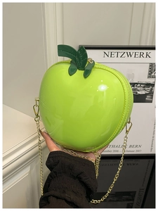 Détail de ce sac pomme vert brillant avec chaîne dorée et décoration de feuille