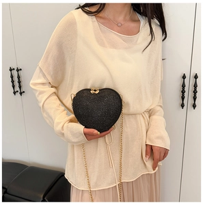 Detail of heart-shaped black sequin crossbody bag with gold chain and dual heart zippers