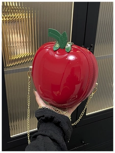 Détail d'un petit sac pomme rouge avec chaîne dorée et décor de feuilles vertes