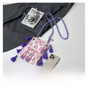 Gros plan d'un mini sac bandoulière ethnique tissé avec franges mauves et motif jacquard