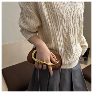 Detail of dark brown velvet clutch with large gold ring handle and metal studs