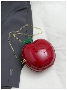 Détail du sac bandoulière pomme rouge avec finition brillante et chaîne dorée