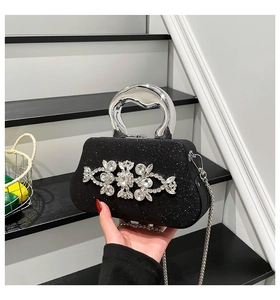 Detail of black rhinestone evening clutch featuring a large crystal floral accent and silver handle