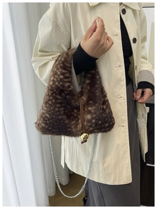Close-up of plush bucket bag with deer print texture and gold sphere charm