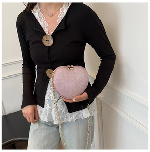 Macro detail of a pink heart-shaped sequin crossbody bag with a gold metal chain strap