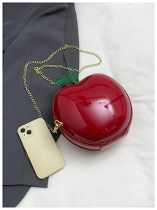 Mini sac pomme avec chaîne dorée montrant la taille réelle à côté d'un téléphone