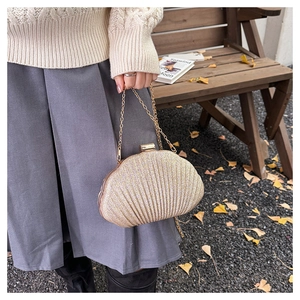 Dettaglio di una pochette a conchiglia dorata scintillante con paillettes e catena