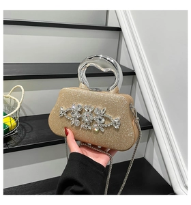 Macro detail of gold evening bag with crystal flower clusters and silver metal handle