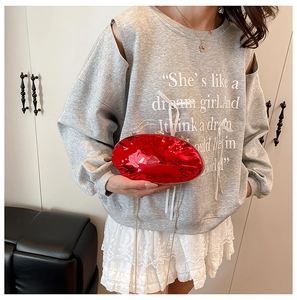 Clutch da sera ovale rossa metallizzata lucida con sottile tracolla dorata su modella