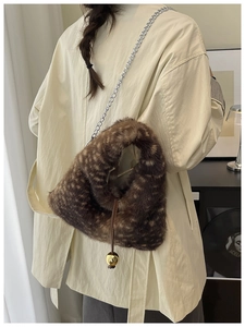 Detail of brown plush crossbody bag with gold orb drawstring and silver chain strap