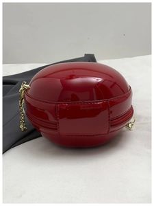 Détail du sac pomme en cuir verni rouge avec chaîne dorée et finition brillante