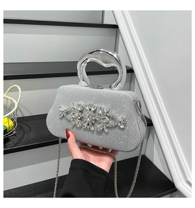 Close-up of sparkling silver glitter evening bag with crystal flower and metal handle