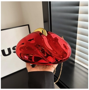 Detail of red acrylic evening clutch with gold clasp and chain strap held in hand