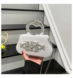Detail of white crystal evening clutch with luxury metal handle and sparkling rhinestone decor