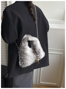 Detail of faux fur crossbody bag with silver chain and gold sphere pendant on model