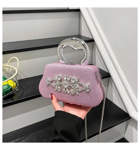 Close-up of pink glitter evening bag featuring large rhinestone flowers and silver handle