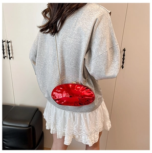 Borsa da sera ovale rosso metallizzato con catena dorata indossata da modella