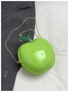 Détail du sac bandoulière vert en forme de pomme avec fini brillant et chaîne dorée