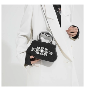 Detail of black shimmer evening clutch with silver flower rhinestones and metal handle