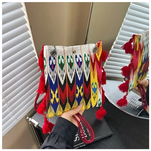 Détail du sac cabas tissé ethnique avec motifs jacquard colorés et pompons rouges