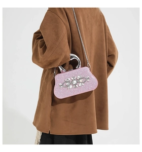 Close-up of a pink sequin evening bag with crystal accents and a silver metal handle
