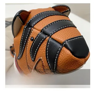 Close-up of orange litchi grain leather texture and stitching on a tiger-shaped bag