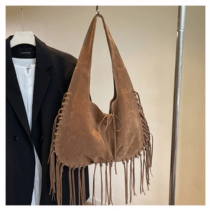 Close-up of caramel suede tote bag featuring delicate tassels and drawstring bow knot
