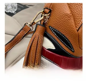 Detail of tiger bag featuring brown lychee leather, tassels, and gold metal hooks