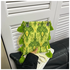 Gros plan du sac cabas ethnique vert montrant des motifs tissés et des détails de franges